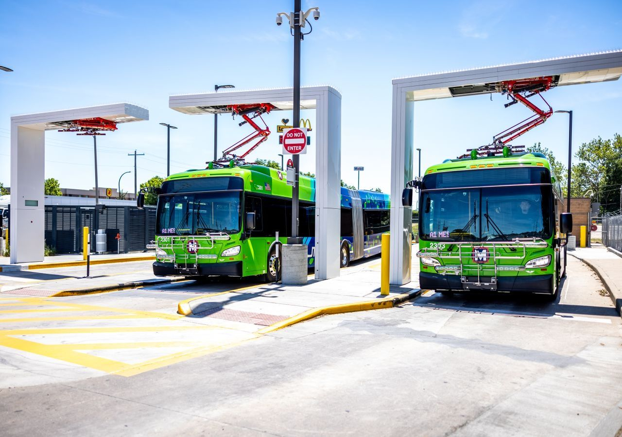 Flota kilkunastu białych elektrycznych autobusów stoi w rządku na placu zajezdni nocą
