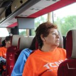 Autobus jedzie autostradą z pasażerami patrzącymi przez okna na rozległe pola i lasy