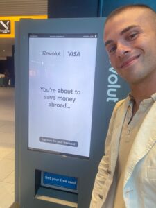 Turysta trzyma kartę Revolut i portfel z euro na tle zagranicznego lotniska